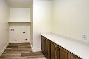 Washroom with cabinets, hardwood / wood-style floors, electric dryer hookup, and washer hookup