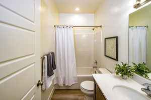 Full bathroom with toilet, hardwood / wood-style flooring, shower / tub combo, and vanity