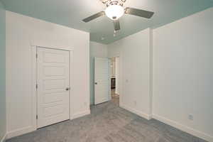 Unfurnished bedroom featuring a closet, light colored carpet, and ceiling fan