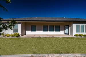 Rear view of house with a yard and a patio