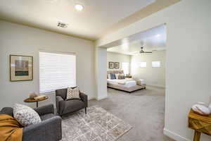 Carpeted living room with ceiling fan and plenty of natural light