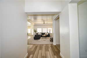 Corridor with a raised ceiling and light hardwood / wood-style flooring