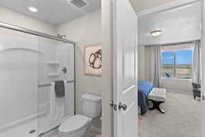 Bathroom with toilet, a shower with shower door, and a textured ceiling