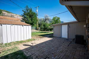 View of patio / terrace featuring central AC unit and a storage unit