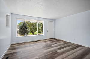 Unfurnished room featuring a wealth of natural light, wood-type flooring, and a textured ceiling