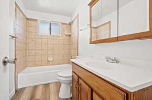 Full bathroom featuring hardwood / wood-style floors, tiled shower / bath, toilet, and vanity