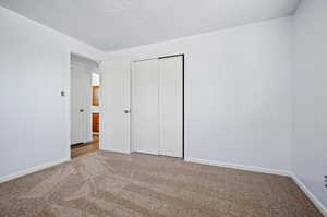 Unfurnished bedroom featuring a closet and light colored carpet