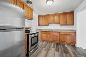 Kitchen featuring light stone countertops, wood-type flooring, stainless steel appliances, and sink