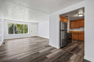 Kitchen with stainless steel appliances, dark hardwood / wood-style flooring, and a textured ceiling