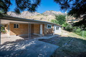 Rear view of property featuring a mountain view, a yard, and a patio