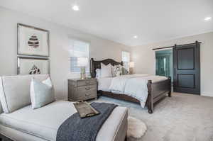 Bedroom with a barn door and carpet floors