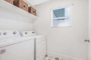 Washroom with light tile patterned floors and washer and dryer