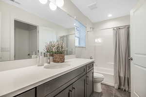 Full bathroom with tile patterned flooring, toilet, shower / tub combo with curtain, and vanity