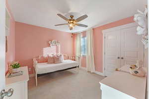 Carpeted bedroom featuring ceiling fan and a closet