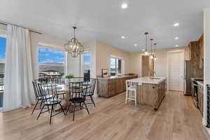 Dining space featuring light hardwood / wood-style flooring, sink, and a notable chandelier