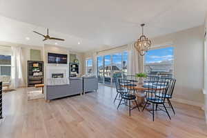 Dining room with light hardwood / wood-style flooring and ceiling fan with notable chandelier