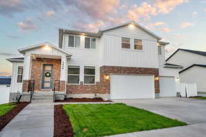 View of front facade featuring a garage and a yard