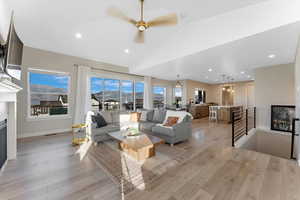 Living room featuring light wood-type flooring, lofted ceiling, a fireplace, and ceiling fan