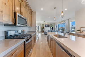 Kitchen featuring a notable chandelier, appliances with stainless steel finishes, hanging light fixtures, sink, and light wood-type flooring