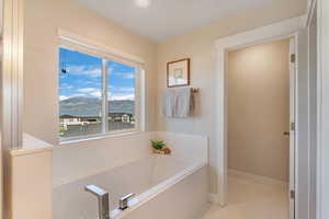 Bathroom featuring a healthy amount of sunlight, a bathing tub, a water and mountain view, and tile patterned floors