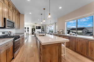 Kitchen with light wood-type flooring, appliances with stainless steel finishes, a center island with sink, and sink