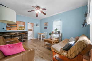 Living room with a textured ceiling, ceiling fan, and light hardwood / wood-style floors