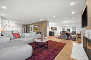 Living room featuring light wood-type flooring, a fireplace, and a chandelier