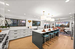 Kitchen featuring light wood-type flooring, decorative light fixtures, sink, a kitchen breakfast bar, and a kitchen island