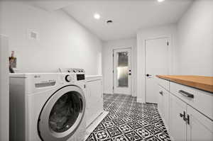 Laundry room featuring cabinets, dark tile patterned floors, and washing machine and clothes dryer