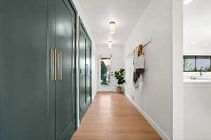 Corridor with a wealth of natural light, sink, and light wood-type flooring