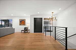 Corridor featuring light wood-type flooring and a chandelier