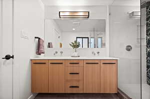 Bathroom featuring tiled shower and vanity