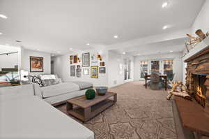 Living room with french doors, a stone fireplace, and carpet