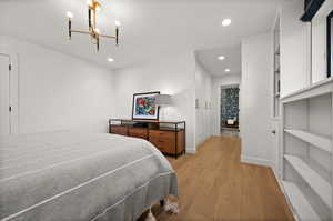 Bedroom with a notable chandelier and light hardwood / wood-style floors