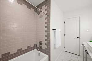 Bathroom featuring tile patterned floors, tiled shower / bath combo, and vanity