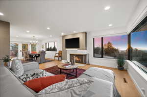 Living room with a premium fireplace, a notable chandelier, and light wood-type flooring