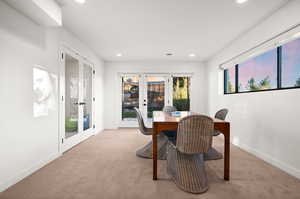 Carpeted dining area with french doors