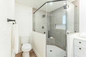 Bathroom featuring toilet, wood-type flooring, and an enclosed shower