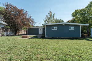 Back of property with a fire pit and a lawn