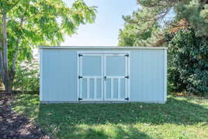 View of outbuilding with a lawn