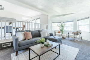 Carpeted living room featuring beamed ceiling and a textured ceiling