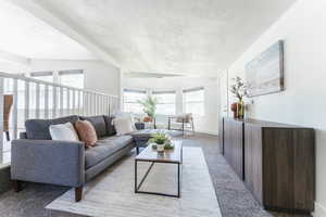 Living room with a textured ceiling, carpet flooring, and beam ceiling