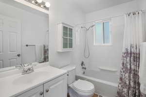 Full bathroom featuring shower / bathtub combination with curtain, toilet, and vanity