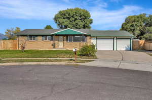 Ranch-style house featuring a garage and a front lawn