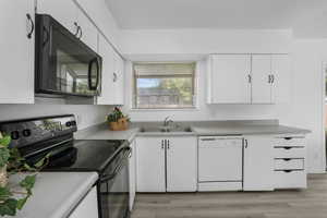 Kitchen with white cabinetry, light vinyl wood-style flooring, sink, white dishwasher, and range with electric cooktop