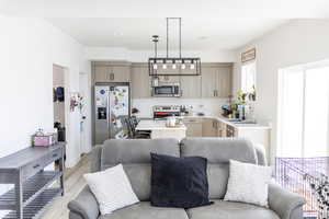 Kitchen featuring decorative light fixtures, stainless steel appliances, light brown cabinetry, sink, and light hardwood / wood-style floors