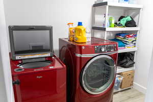 Laundry room featuring washing machine and clothes dryer and light hardwood / wood-style flooring