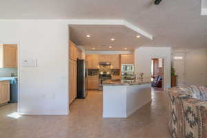 Kitchen featuring dark stone countertops, tasteful backsplash, light tile patterned floors, light brown cabinetry, and appliances with stainless steel finishes