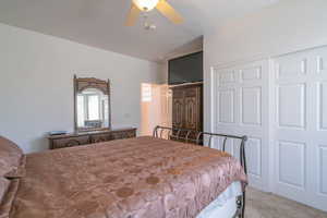 Carpeted bedroom featuring ceiling fan and a closet