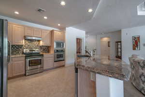 Kitchen with light tile patterned floors, light brown cabinetry, stainless steel appliances, and sink